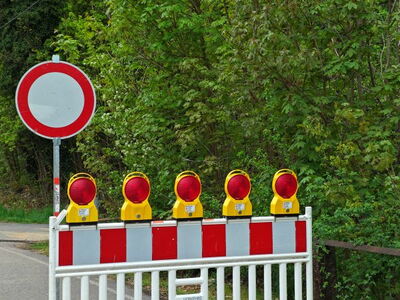 Links im Bild: Verkehrsschild "Einfahrt verboten" | Rechts daneben: Baustellenabsperrung mit fünf Warnleuchten